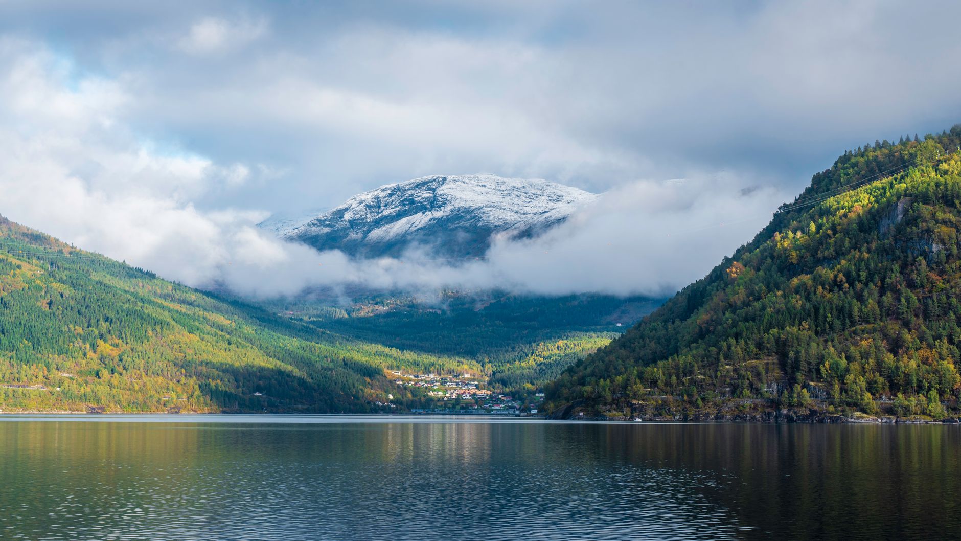 Panoramic view of a vibrant Scandinavian city, possibly Stockholm or Copenhagen, with traditional colorful buildings by the waterfront, and a glimpse of serene natural landscapes or fjords in the background, suggesting a blend of urban and nature exploration.