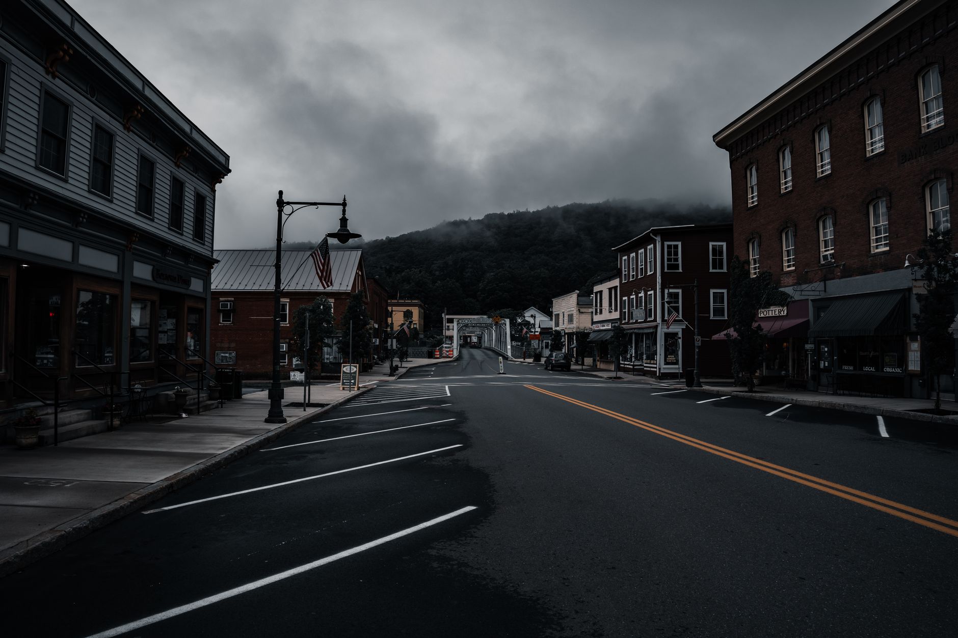 A wide shot capturing the unique and varied architecture of an overlooked American small town, with a mix of historic buildings and natural landscape, hinting at hidden stories.