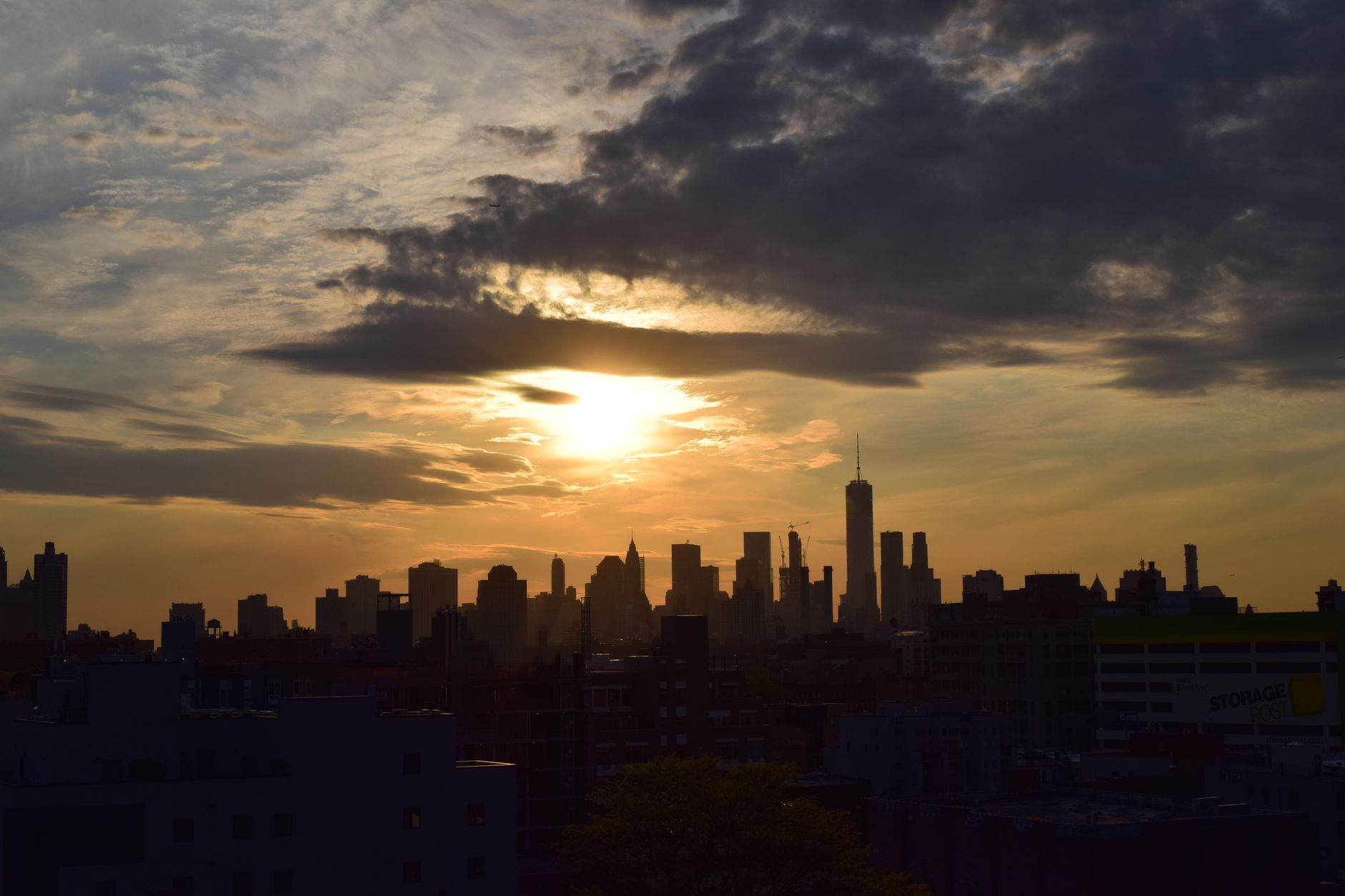 A wide shot of the New York City skyline at sunset, showing both the lush greenery of Central Park and the illuminated buildings of Midtown.