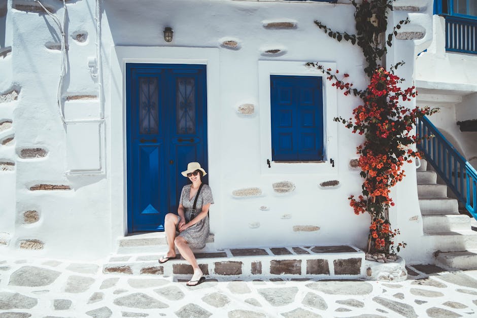 A picturesque scene in Anafiotika, Athens, featuring narrow, winding cobblestone stairs flanked by traditional whitewashed houses adorned with vibrant pink bougainvillea, all under a clear blue sky.