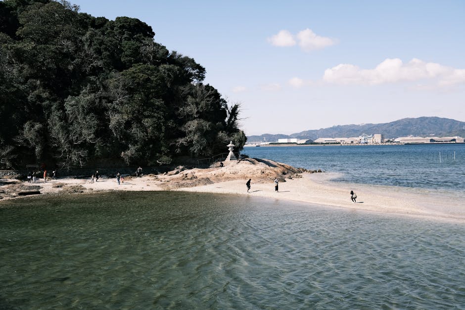 Iconic yellow pumpkin sculpture by Yayoi Kusama on a pier overlooking the Seto Inland Sea on Naoshima Island, Japan, with blue skies and calm water.