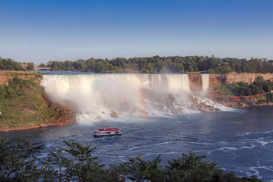 Panoramic view of Niagara Horseshoe Falls on the Canadian side, showing the immense curved waterfall, mist rising, and the Niagara River below.
