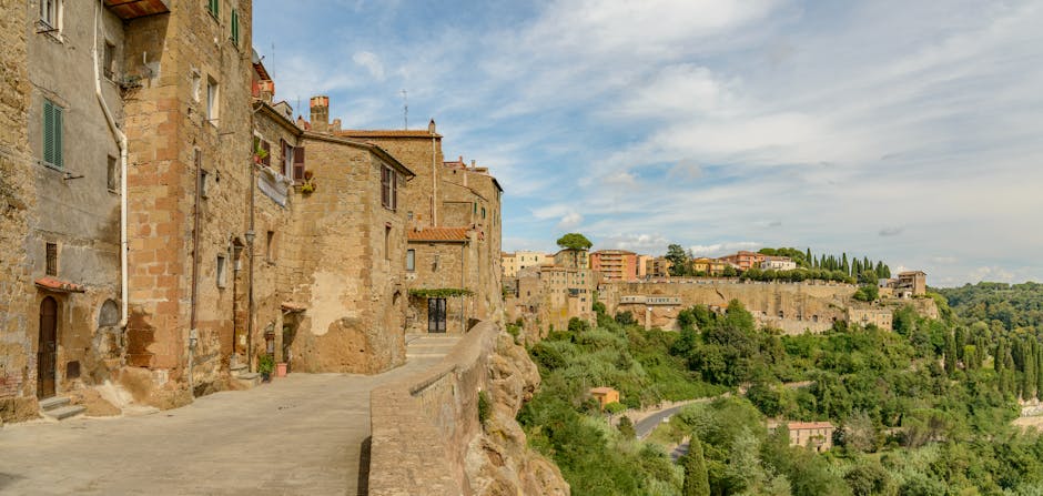 Panoramic view of Pitigliano, Italy, a medieval village dramatically built into golden tufa cliffs, with its ancient buildings appearing to emerge organically from the rock.
