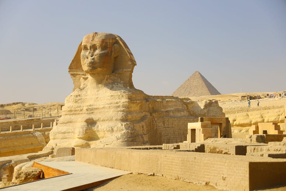 The Great Pyramid of Khufu and the Great Sphinx of Giza bathed in golden sunlight, with the vast desert stretching behind them.